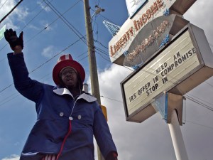 Anthony Roberts is a seasonal worker for Liberty Income Tax Services on the corner of Madison and Edgewood avenues. He waves and paces around in the intermittent snow on March 25. (James Figy)